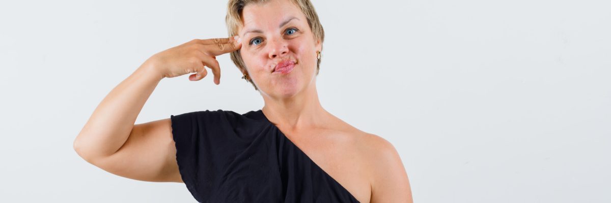 charming lady touching her head with finger in black blouse front view.