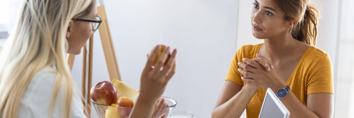 Female nutritionist giving consultation to patient. Making diet plan. Young woman visiting nutritionist in weight loss clinic